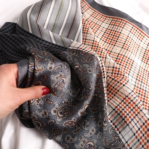 Macro detail of houndstooth and paisley silk scarves showing soft fabric texture