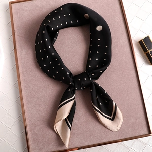 Elegant black polka dot silk scarf tied in a bow on a velvet tray with a lipstick