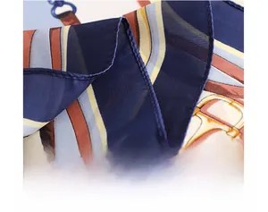 Detailed close-up showing machine-stitched edge on a navy and caramel silk satin scarf