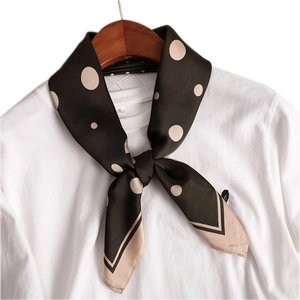 Elegant dark green silk scarf with large beige polka dots displayed on a wooden hanger