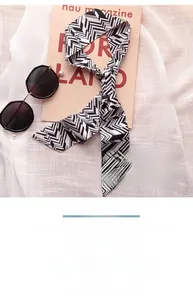 Detail of elegant black and white herringbone skinny silk scarf on pink background
