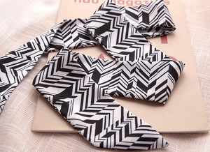 Detail of a narrow black and white geometric twilly scarf on a stylish magazine backdrop