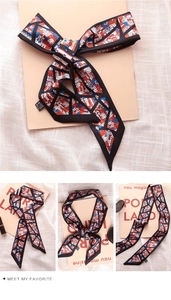 Close-up of silk twilly scarf with colorful Nordic house print and black edge piping