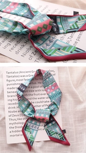 Detailed close-up of a floral geometric silk scarf with contrast edging and smooth texture