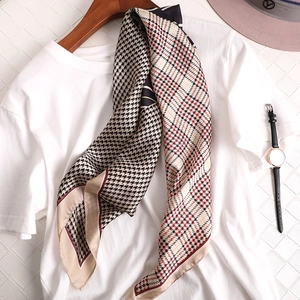 Détail d'un foulard en soie avec motif pied-de-poule et carreaux rouge-noir sur t-shirt