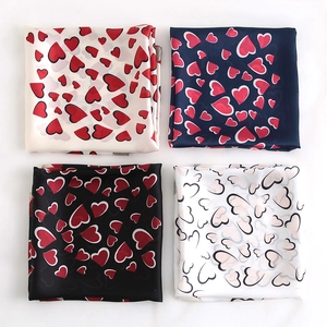 Détails de quatre foulards en soie à motifs cœurs en beige, bleu marine, noir et blanc