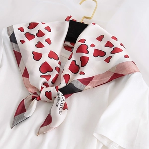 Détail d'un foulard en soie avec imprimé cœurs rouges et bordure géométrique élégante