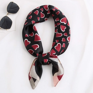 Gros plan d'un foulard en soie avec motifs cœurs rouges et bords rayés sur tissu blanc