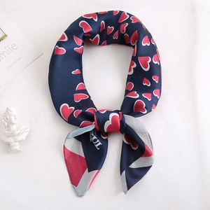 Détail d'un foulard en satin bleu marine avec motifs de cœurs rouges et nœud élégant