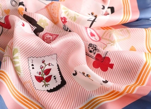 Gros plan d'un foulard en soie avec des motifs de cartes à jouer et des fleurs