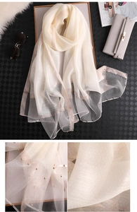 Detail of ivory silk scarf showing golden beads and shimmering edge texture