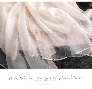 Detailed close-up of sun protection silk scarf with gold beads and pink stripe edge