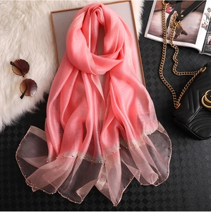 Detail of pink lightweight silk scarf featuring delicate pearl beading and gold trim edge