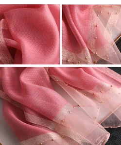 Detail of pink silk scarf showing square jacquard texture and golden beaded edge