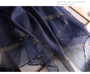 Detailed shot of dark blue scarf with gold bead trim and shiny silk stripes