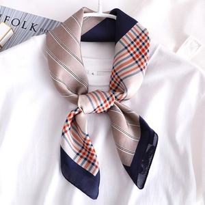 Détail d'un foulard en soie à rayures et carreaux noué sur un t-shirt blanc
