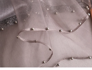 Detail of light purple silk scarf featuring silver bead edges and shimmering accents