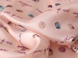 Gros plan sur la texture satinée soyeuse avec lettrage violet et imprimé floral rose