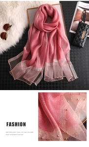 Detailed macro view of pink silk scarf showing elegant gold trim and pearl accents