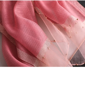Close-up of pink silk shawl featuring gold bead trim and delicate jacquard patterns