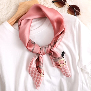 Détail du foulard en soie rose avec imprimé chaîne dorée et motifs géométriques chic