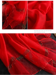 Close-up of red silk scarf with gold beads and metallic thread detail