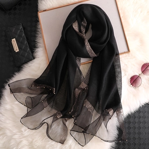 Women's black silk scarf with gold stripes and pearl beads on a white fur background