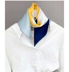 Close-up of geometric pattern silk scarf tied on white shirt collar with yellow and blue tones