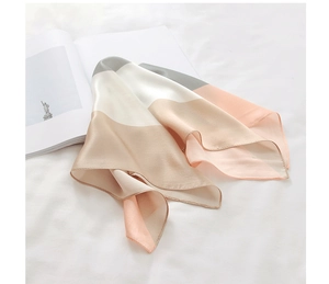 Detailed close-up of smooth stitched edges on a color-block satin silk scarf