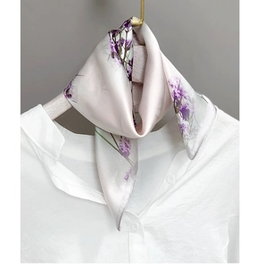 Detailed close-up of lavender floral silk scarf tied on a classic white linen shirt