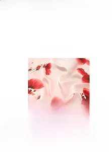 Macro detail of silk-like light pink fabric featuring vibrant red poppy floral prints