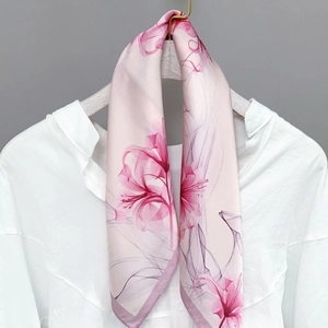 Pink silk-like scarf with floral lily pattern on a white wooden hanger with shirt