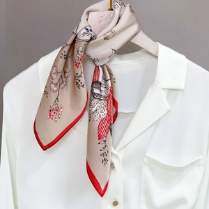 Champagne silk scarf with red border and floral bird prints draped on a white shirt