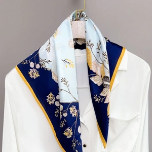 Elegant silk scarf with floral and shell patterns worn over a white shirt
