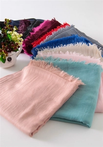 Fan-shaped display of multi-colored cotton linen scarves with fringe edges and soft texture