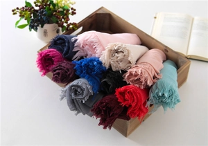 Detail of colorful cotton linen scarves with fringe edges rolled in a wooden tray