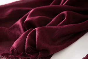 Close-up of deep red cotton linen scarf showing soft fabric texture and frayed tassel edges