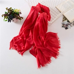 Detail of red cotton linen scarf with tassels draped on a white vintage basket