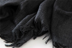 Close-up of the fine fringe edge and natural textured fabric of this dark linen scarf