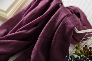 Detailed texture of dark purple cotton linen scarf folded in a white metal basket