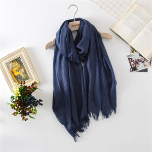 Solid deep blue cotton linen scarf with tassels displayed on a wooden hanger with books