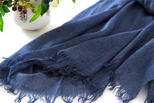 Close-up of indigo cotton-linen scarf fabric texture and natural raw fringe detail