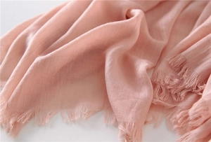 Close-up of light pink cotton linen scarf featuring woven texture and frayed edges