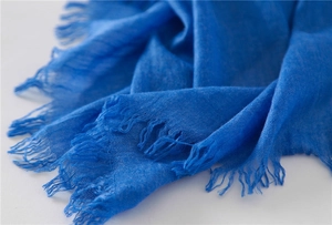 Detailed macro shot of cobalt blue cotton linen scarf with elegant fringe edges and soft texture