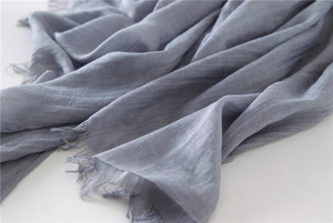 Detail of greyish blue linen cotton scarf showing fabric texture and frayed fringe edges