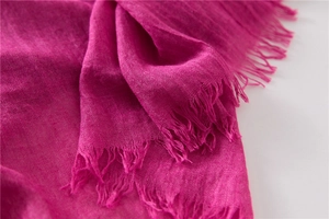 Detail of rose red linen scarf showing breathable woven texture and raw fringe edges
