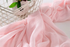 Close-up of light pink cotton linen scarf with soft natural texture and wrinkle detail