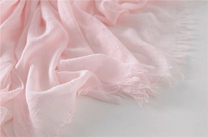 Close-up of light pink cotton linen scarf featuring soft texture and long fringe tassels