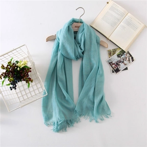 Detail of mint green linen scarf with fine tassel fringe on a wooden hanger