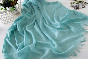 Detail of light blue cotton linen scarf featuring natural crinkled texture and fringed edges